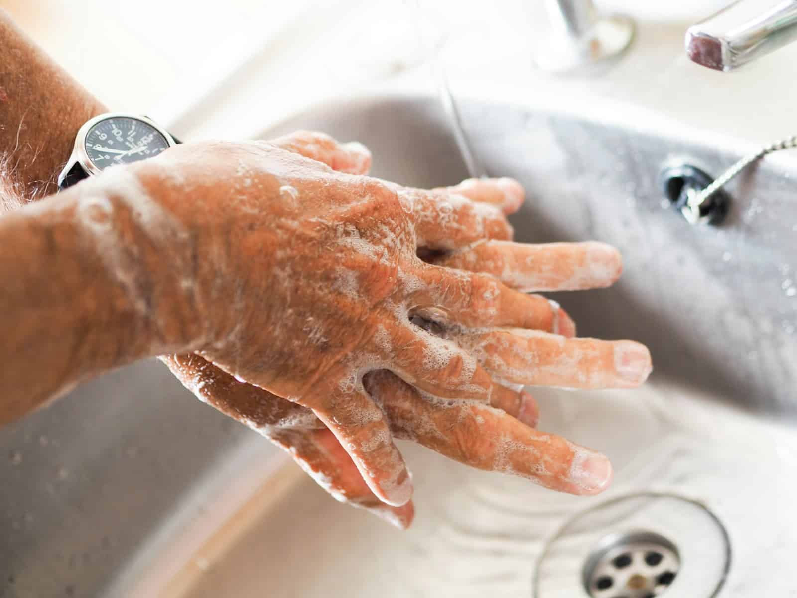 Person washing hands at sink using soap. Handwashing for parasite prevention. Brisbane Livewell Clinic.